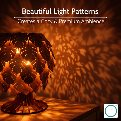 A decorative table lamp with a leaf-shaped shade glows warmly, casting intricate shadow patterns across a wall and tabletop. Text at the top reads 'Beautiful Light Patterns Creates a Cozy & Premium Ambience,' and a small 'LIT!' logo appears in the bottom right corner.